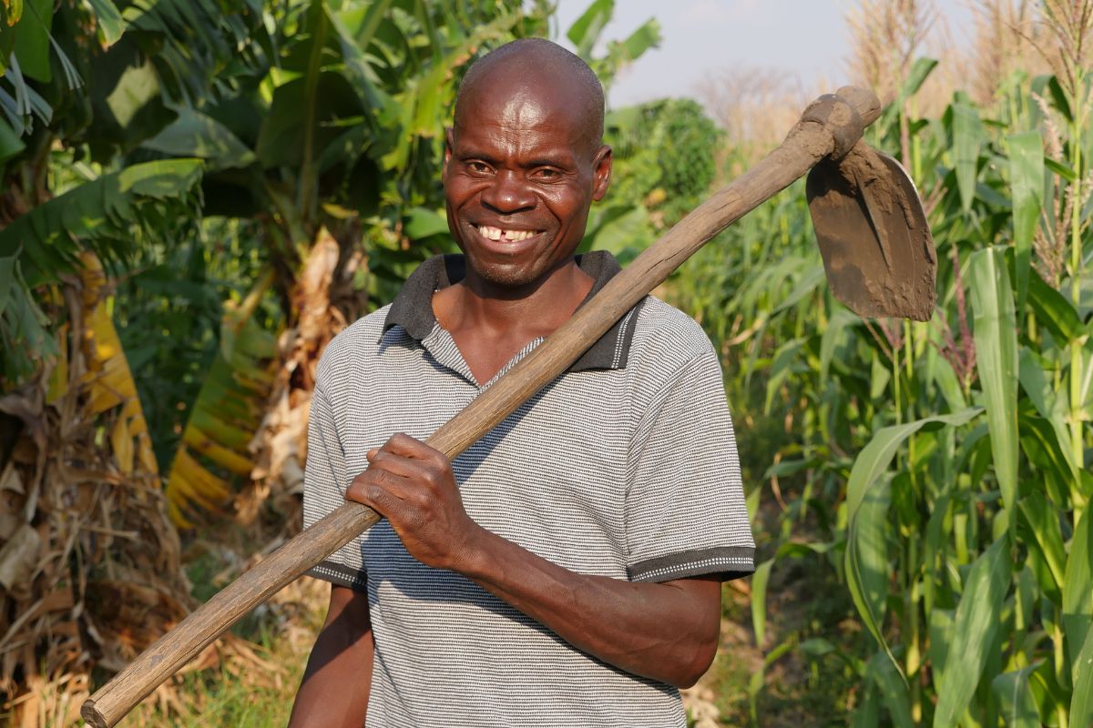 a man stands in a field holding a farming tool