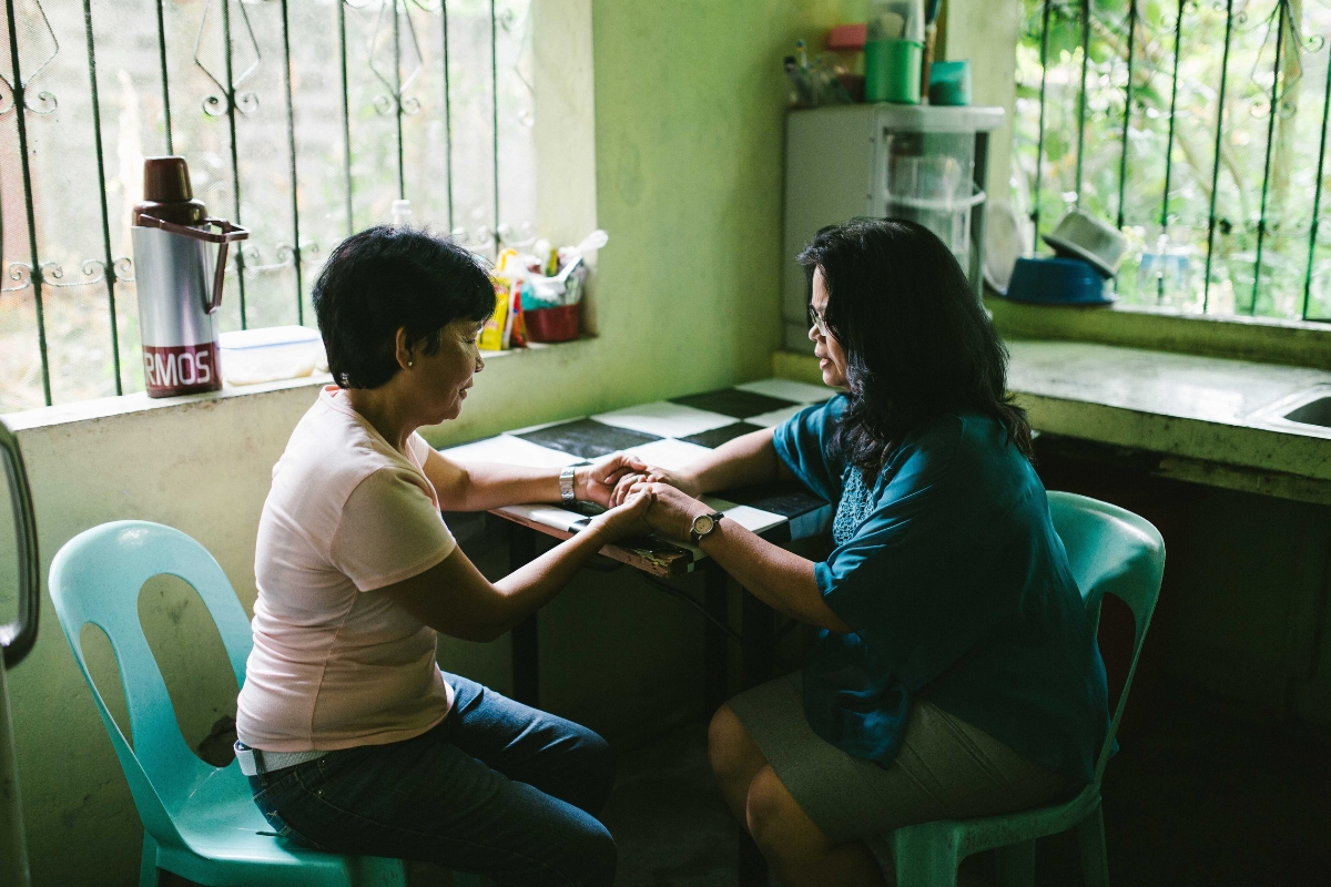 two women hold hands and pray together