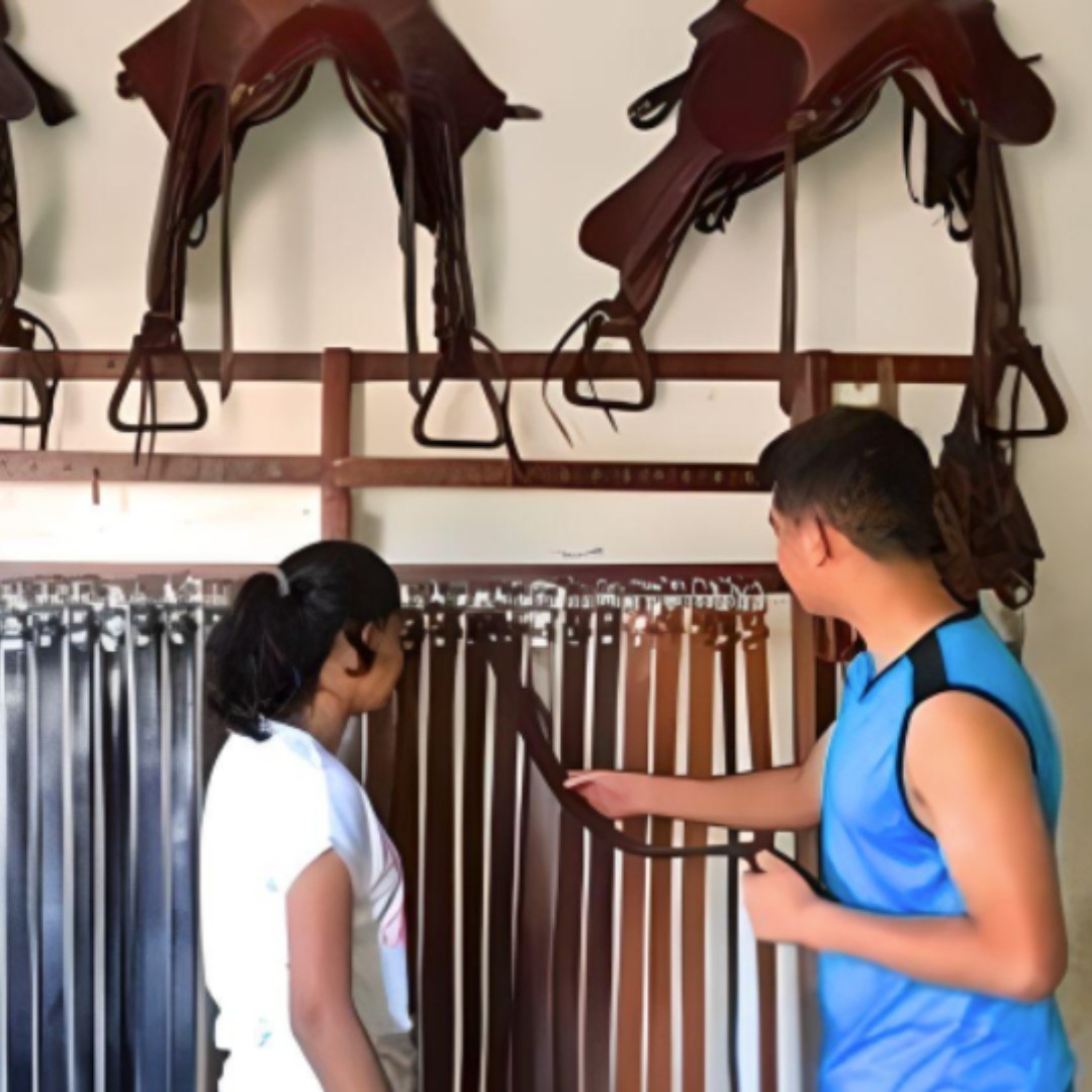 two people look at a clothesrack of leather belts