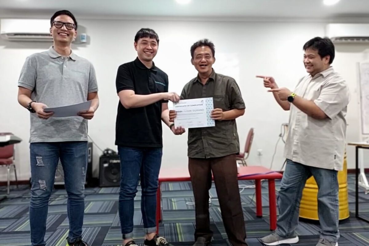 1 man holds a certificate smiling with 3 others around him celebrating