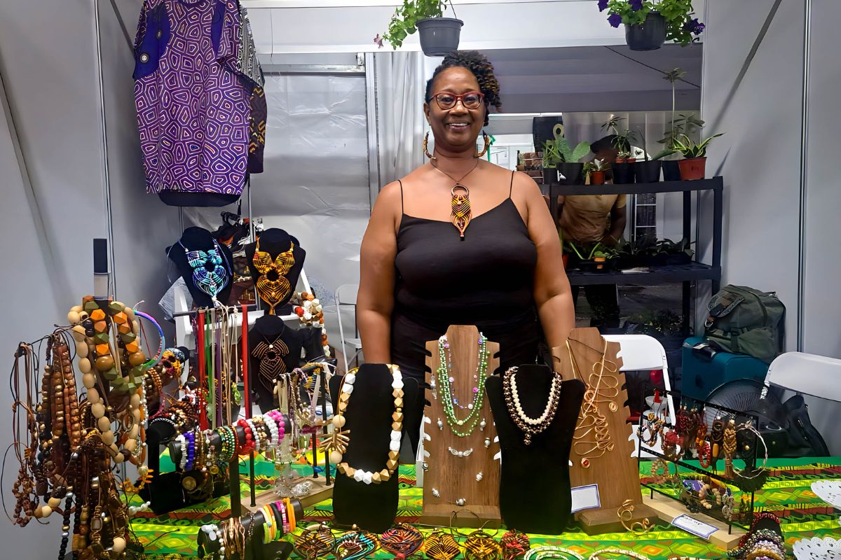a woman stands behind a table displaying jewelry
