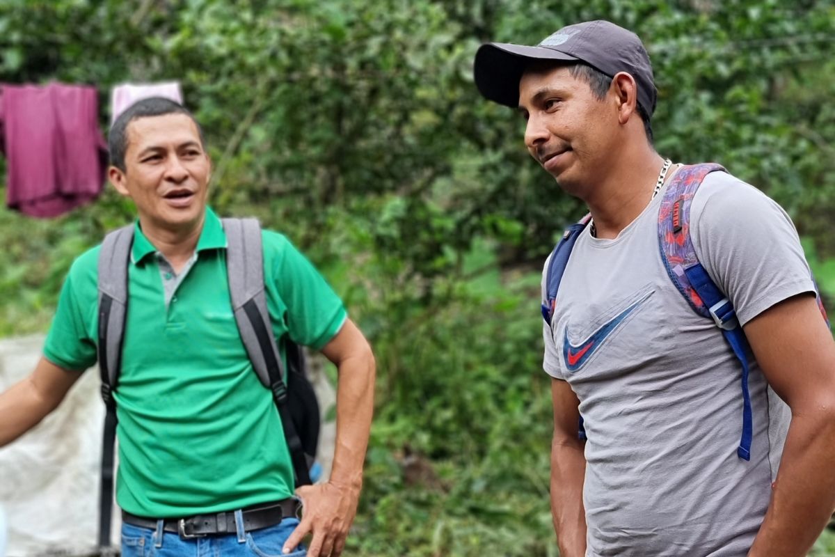 a farmer looks at another farmer who is looking to the right of the photo