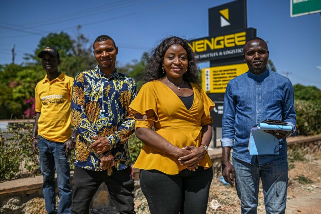 a woman in a yellow shirt stands confidently with her employees
