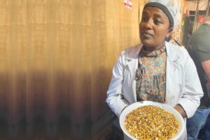 a woman in a white coat holds a plate of nuts and seeds