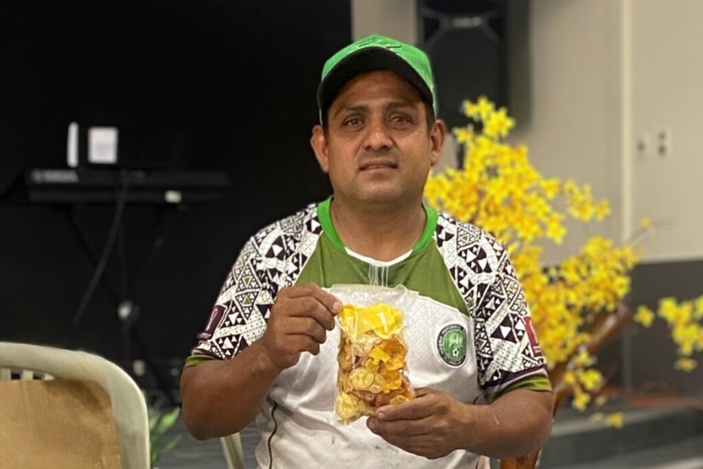 a man sits in a chair holding a plastic bag of chips