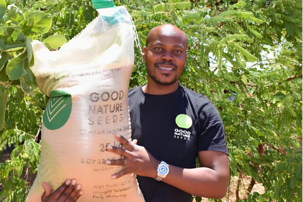 a man holds a big bag of seeds with the words "Good Nature Seeds"