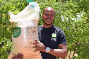 a man holds a big bag of seeds with the words "Good Nature Seeds"