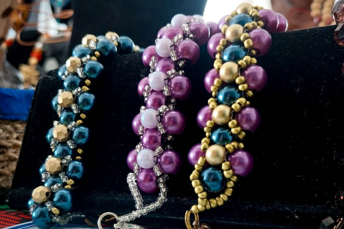 three beaded necklaces on a black display
