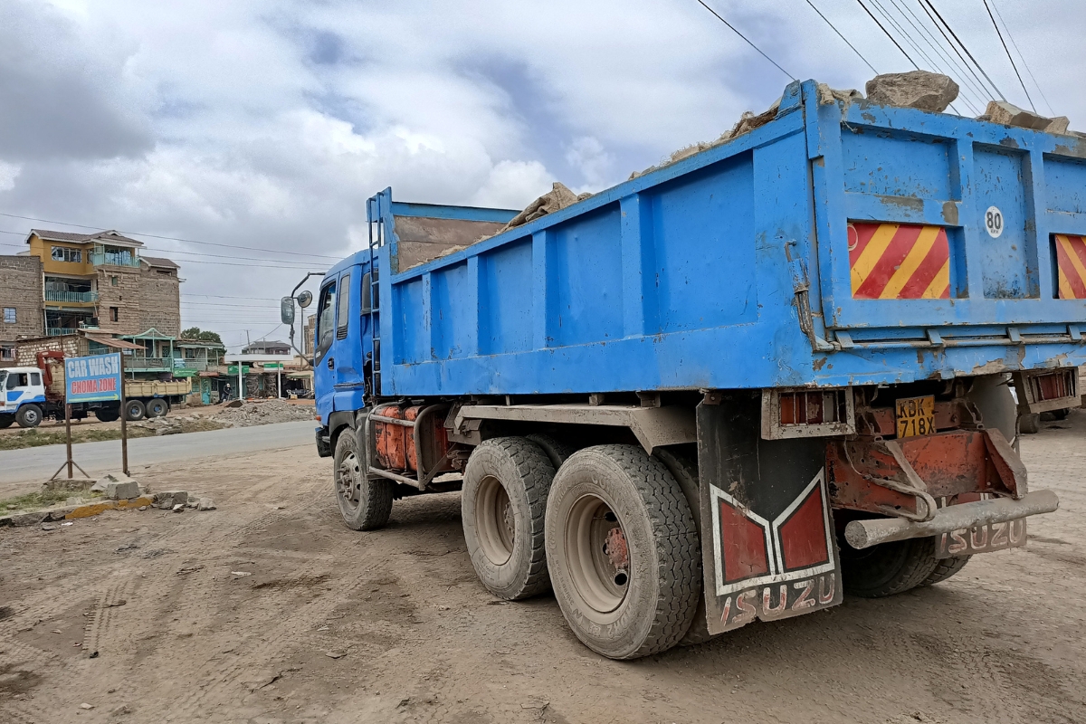 a large blue truck with construction material in the truck bedc