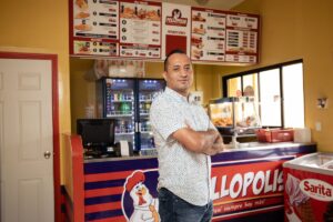 a man stands with arms crossed and smiling in front of a restaurant counter