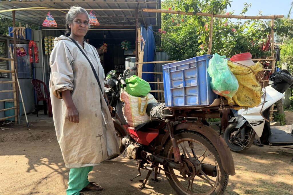 a woman stands next to a red motorbike with a blue crate on the back