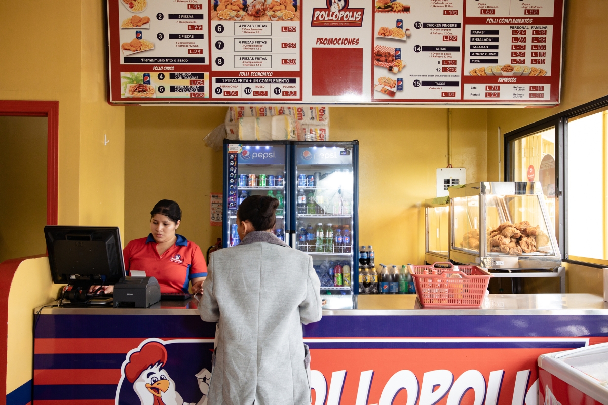 at a restaurant counter a woman looks at a computer screen while another woman stands at the counter