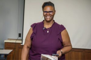 a woman smiles standing in front of a projector screen