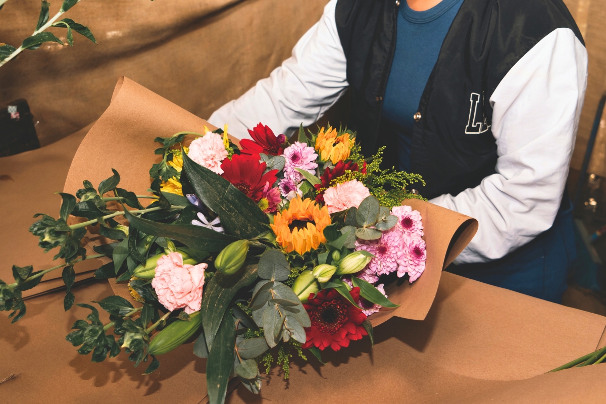 a woman wraps a bouquet in brown paper