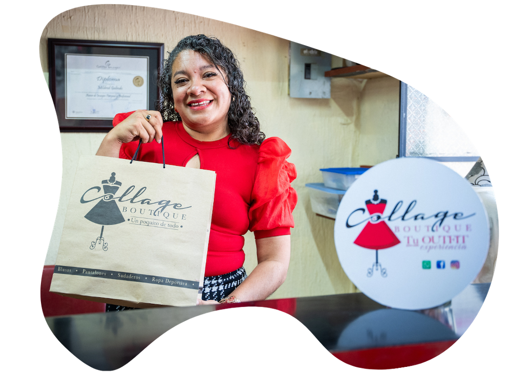a woman in a shop stand behind a counter holding up a paper bag with the shop logo