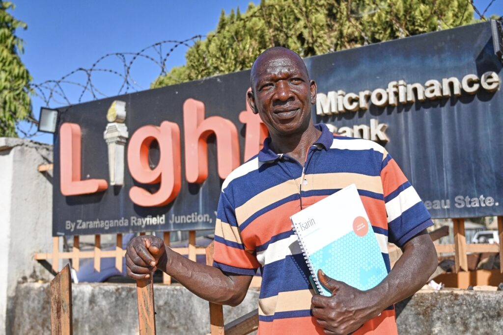 a man stands confidently holding a a notebook