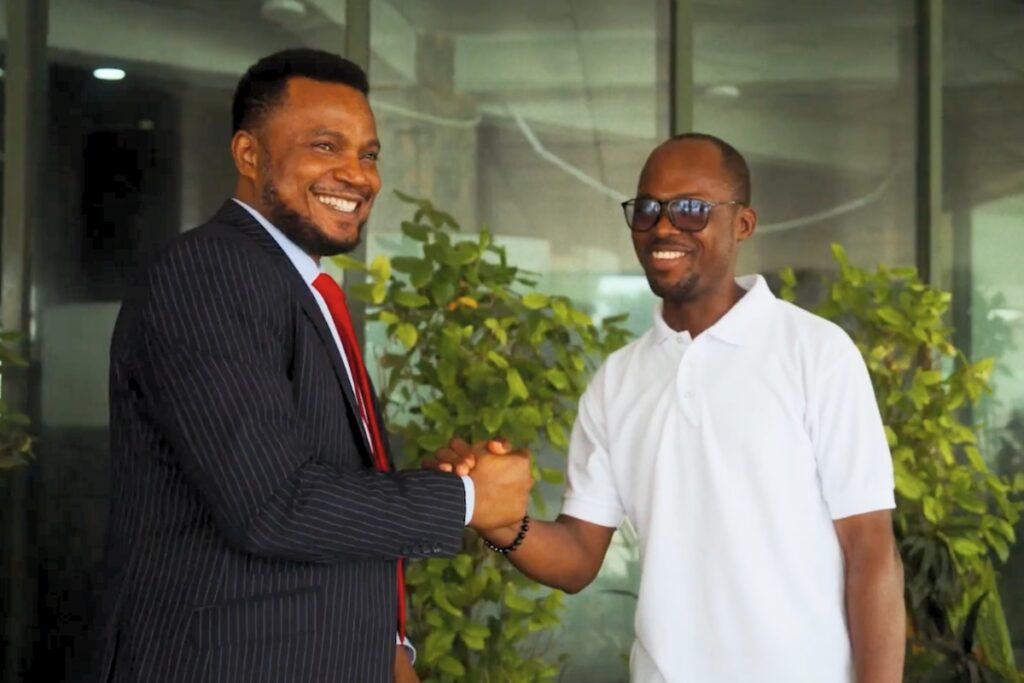 two men shake hands and smile