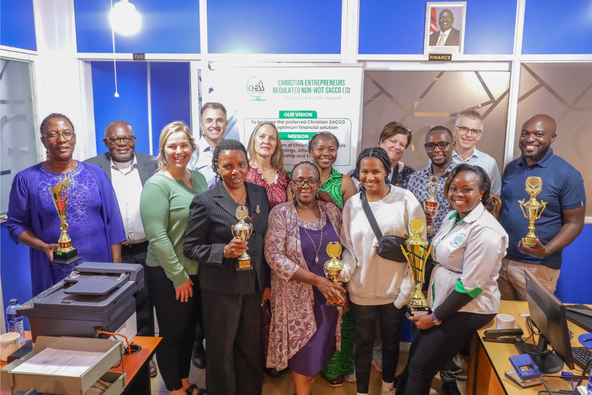 Group of fourteen people pose together in an office space with awards in hand.