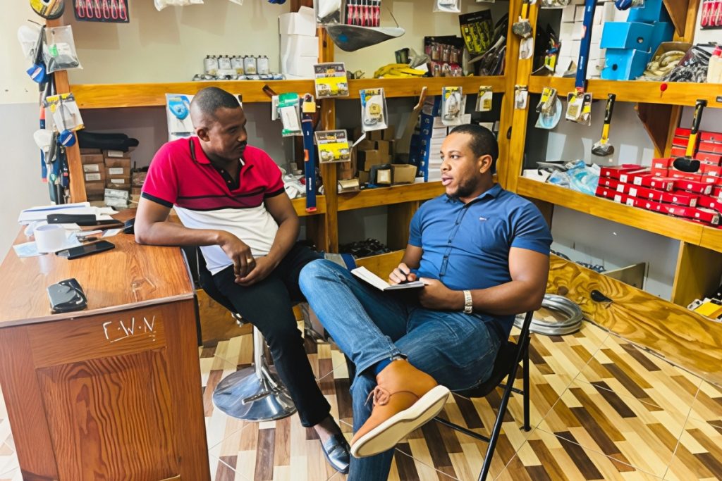 Two men sitting talking together with tools behind them