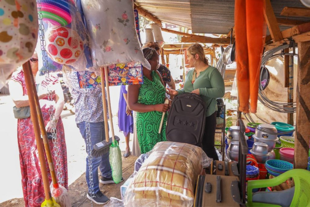 Women look through various wares including pillows, cookware, and suitcases.
