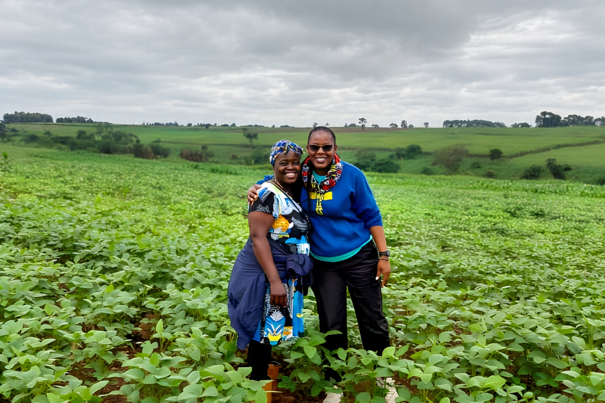 Two smiling women standing arm in arm in a soybean field