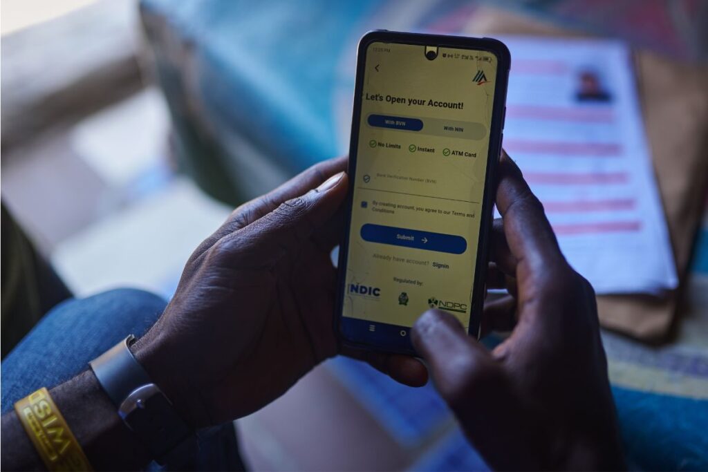 Hands holding a smartphone showing a mobile bank account sign-up screen